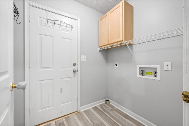 clothes washing area featuring cabinets, light hardwood / wood-style floors, hookup for a washing machine, electric dryer hookup, and a textured ceiling