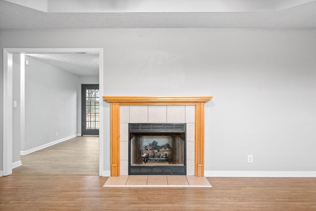 room details featuring a textured ceiling, hardwood / wood-style floors, and a tile fireplace