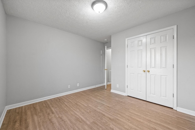 unfurnished bedroom with a closet, a textured ceiling, and light hardwood / wood-style flooring