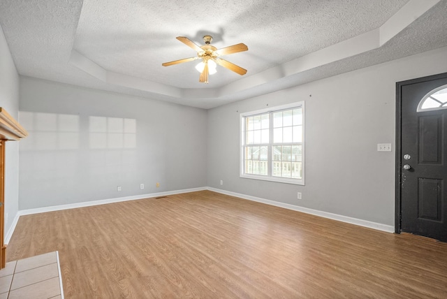 foyer featuring ceiling fan, a raised ceiling, a textured ceiling, and wood-type flooring