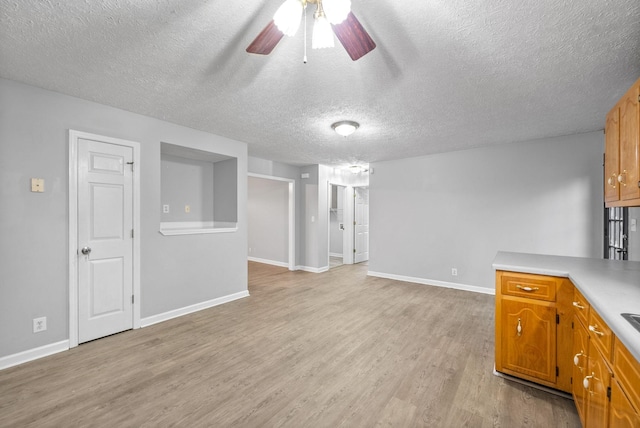 unfurnished living room featuring a textured ceiling, ceiling fan, and light hardwood / wood-style flooring