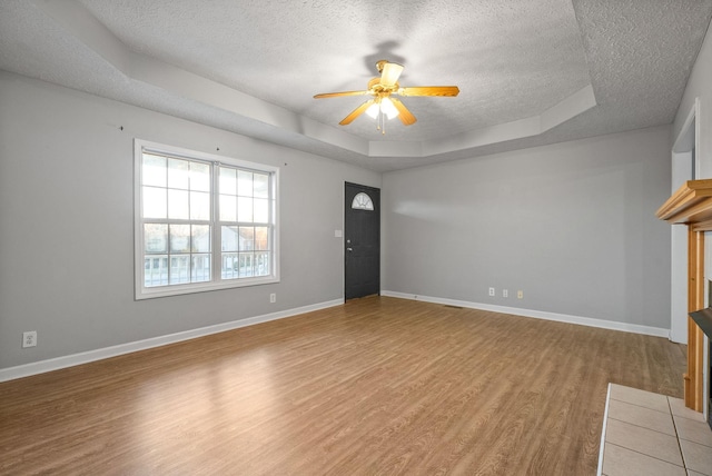 unfurnished living room with a textured ceiling, ceiling fan, a tray ceiling, and wood-type flooring