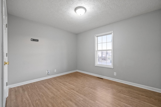 empty room featuring a textured ceiling and wood-type flooring