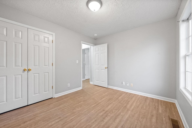 unfurnished bedroom with a closet, a textured ceiling, and light wood-type flooring