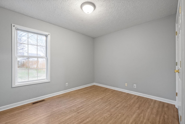 unfurnished room with a textured ceiling and hardwood / wood-style flooring