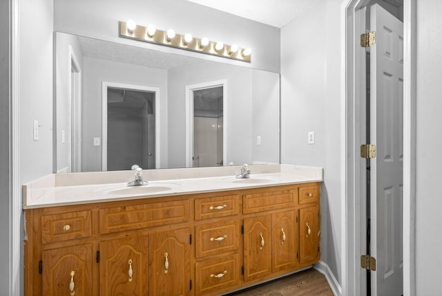 bathroom with a textured ceiling, hardwood / wood-style floors, and vanity