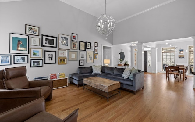 living room with ornate columns, a high ceiling, light hardwood / wood-style floors, and a notable chandelier