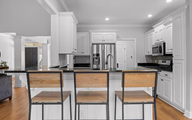 kitchen featuring white cabinets, appliances with stainless steel finishes, and ornamental molding