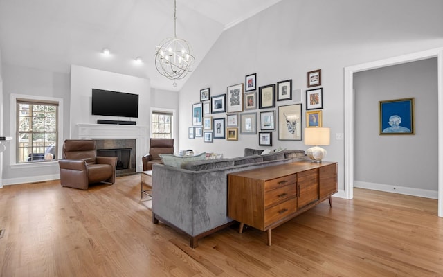 living room with a tile fireplace, light hardwood / wood-style floors, a chandelier, and plenty of natural light