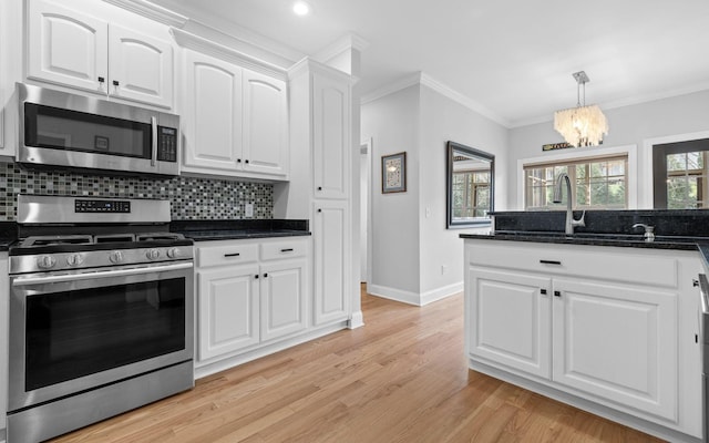 kitchen with a notable chandelier, stainless steel appliances, white cabinetry, and crown molding