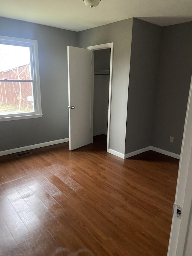 unfurnished bedroom with dark wood-type flooring and a closet