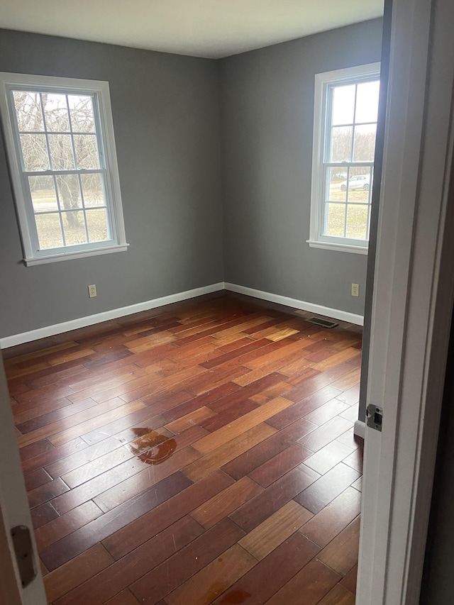 spare room featuring plenty of natural light and dark hardwood / wood-style floors