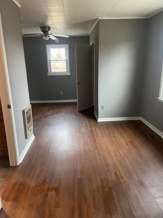 unfurnished bedroom with heating unit, ornamental molding, dark hardwood / wood-style floors, and ceiling fan