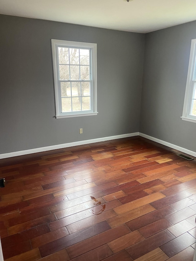 spare room featuring a wealth of natural light and dark hardwood / wood-style flooring