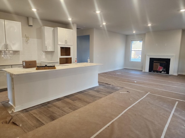 kitchen with a kitchen island, white cabinets, decorative backsplash, and light wood-type flooring