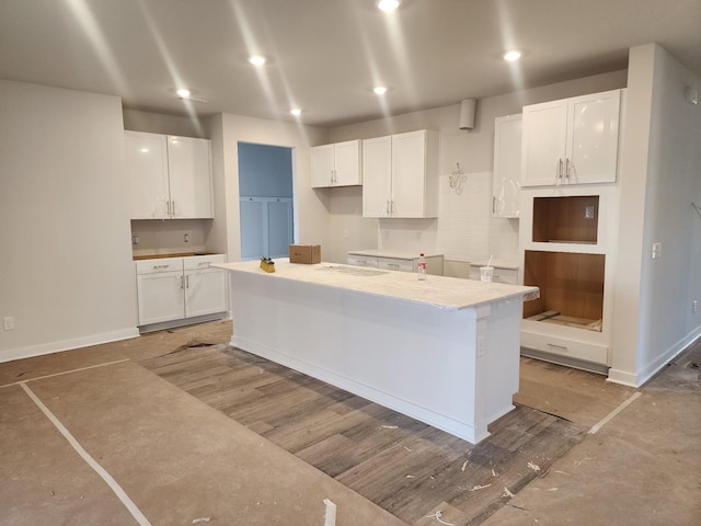 kitchen featuring a kitchen island, white cabinets, and light stone countertops