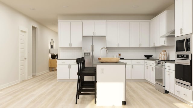 kitchen featuring stainless steel appliances, white cabinetry, wall chimney range hood, and a kitchen island