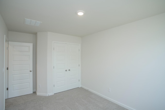 unfurnished bedroom with light colored carpet and a closet