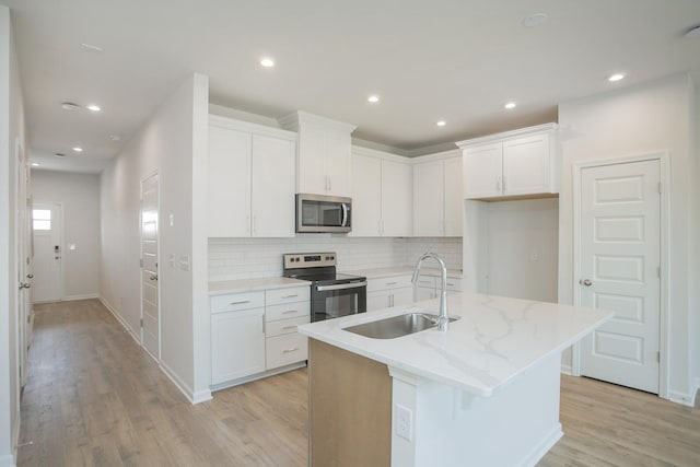 kitchen featuring white cabinetry, appliances with stainless steel finishes, and an island with sink