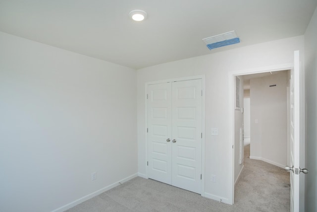 unfurnished bedroom with light colored carpet and a closet