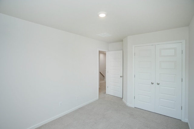 unfurnished bedroom with light colored carpet and a closet