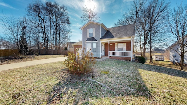 view of front of home with a porch, a front yard, and a storage shed