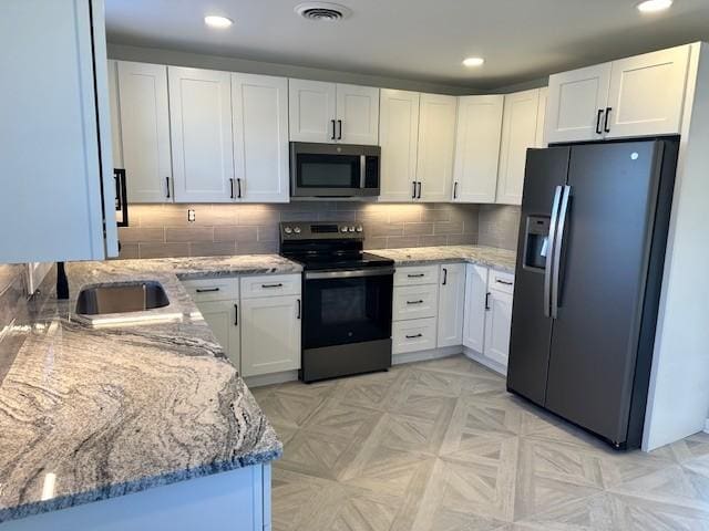 kitchen with stainless steel appliances, sink, white cabinets, decorative backsplash, and light stone countertops