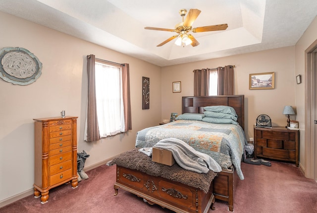 carpeted bedroom featuring a raised ceiling and ceiling fan