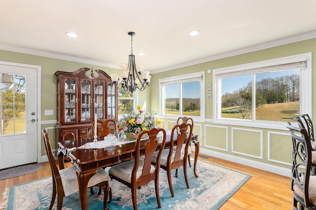 dining area featuring light wood-type flooring, an inviting chandelier, and ornamental molding