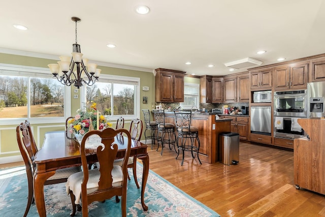 dining space with sink, a chandelier, ornamental molding, and dark wood-type flooring