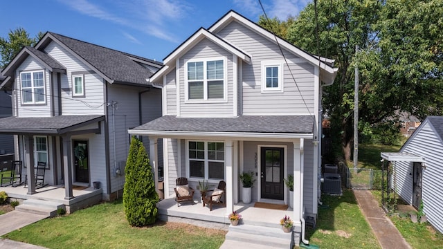 front of property featuring a porch, cooling unit, and a front yard