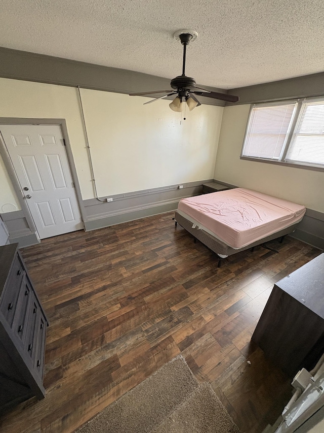 bedroom featuring a textured ceiling, ceiling fan, and dark hardwood / wood-style flooring