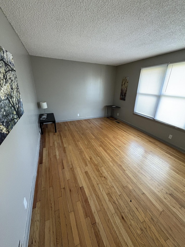 unfurnished living room with light wood-type flooring and a textured ceiling