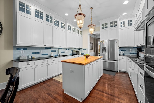 kitchen with a kitchen island, decorative light fixtures, white cabinetry, and appliances with stainless steel finishes