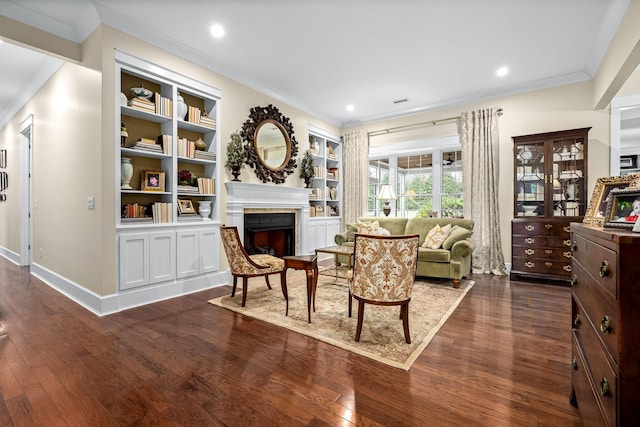 sitting room with dark hardwood / wood-style flooring, crown molding, and built in shelves