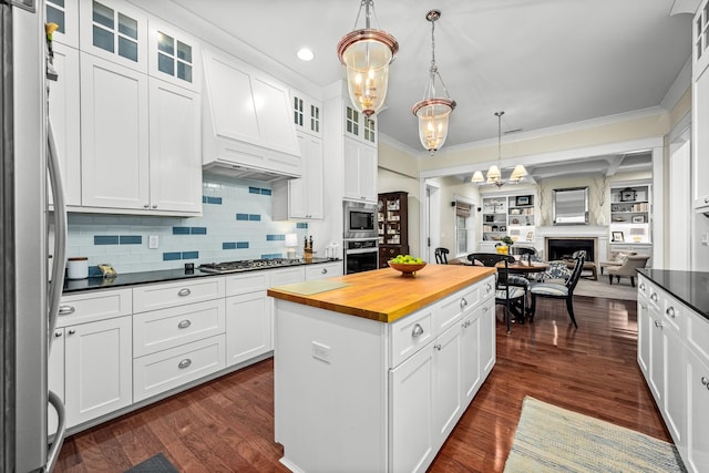 kitchen featuring a kitchen island, white cabinetry, hanging light fixtures, and appliances with stainless steel finishes