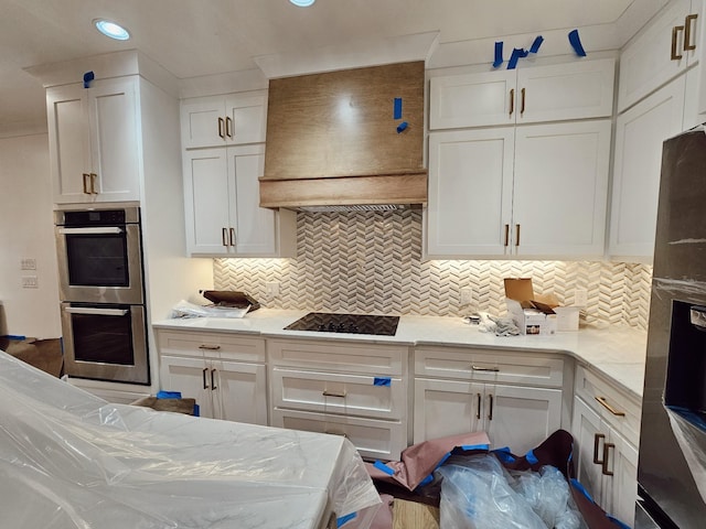 kitchen with white cabinetry, custom exhaust hood, decorative backsplash, stainless steel double oven, and black electric stovetop