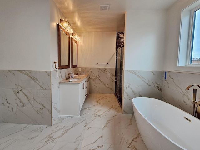 bathroom with vanity, tile walls, and a bathtub