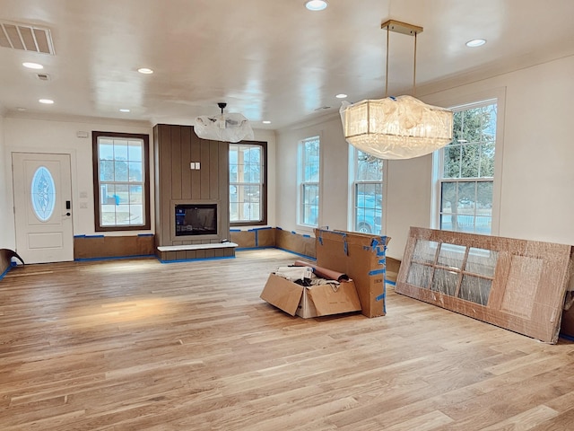 living room featuring a fireplace, a chandelier, ornamental molding, and light hardwood / wood-style flooring