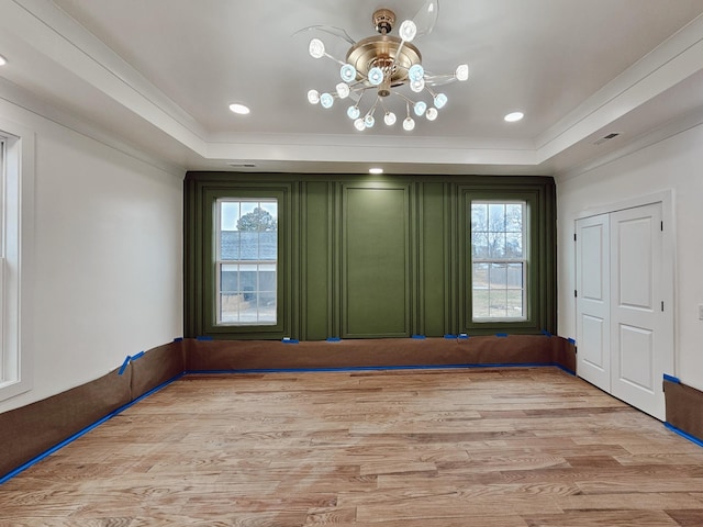 unfurnished room with light hardwood / wood-style floors, ornamental molding, and a tray ceiling