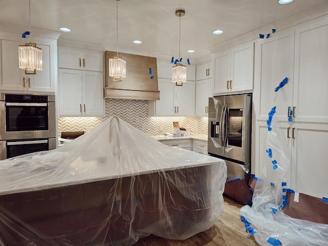 kitchen featuring light stone countertops, appliances with stainless steel finishes, hanging light fixtures, and white cabinetry