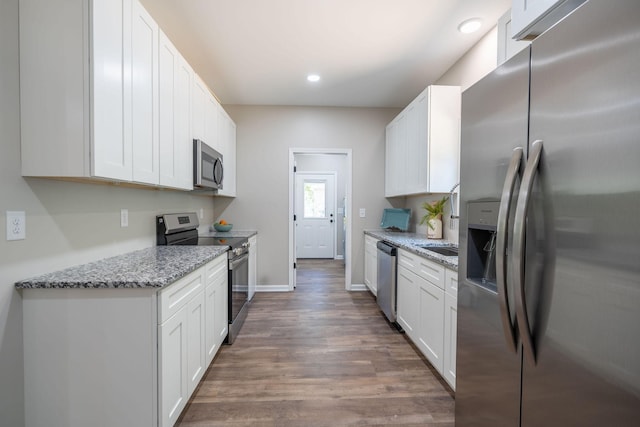 kitchen with stainless steel appliances, white cabinetry, dark hardwood / wood-style floors, and light stone countertops