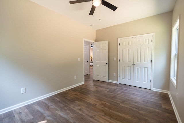 unfurnished bedroom featuring dark wood-type flooring, ceiling fan, a closet, and multiple windows