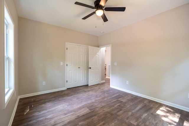 unfurnished bedroom featuring ceiling fan, dark hardwood / wood-style flooring, and a closet