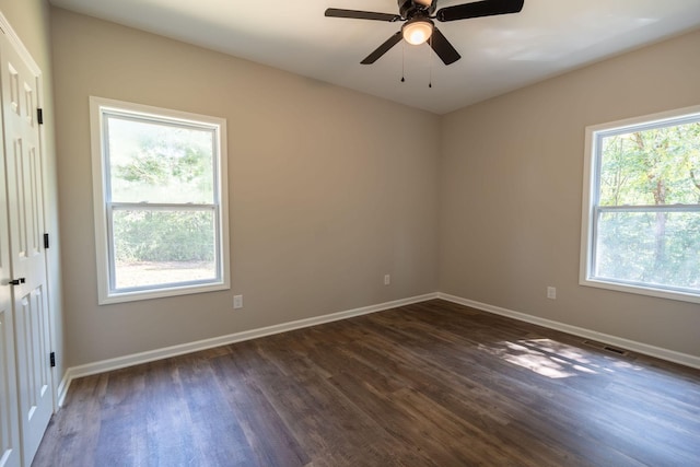 spare room with dark wood-type flooring, ceiling fan, and a healthy amount of sunlight