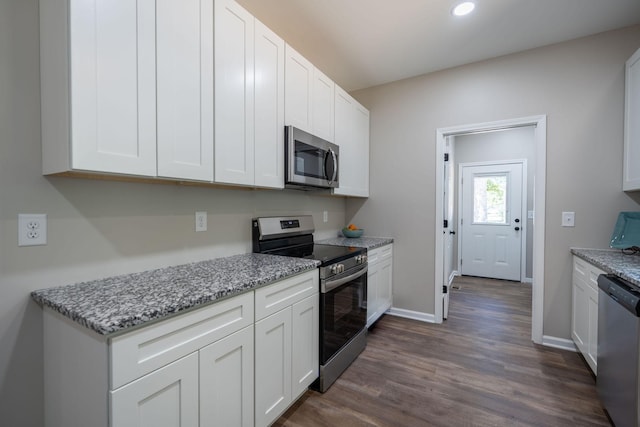 kitchen featuring stainless steel appliances, dark wood-type flooring, light stone countertops, and white cabinetry