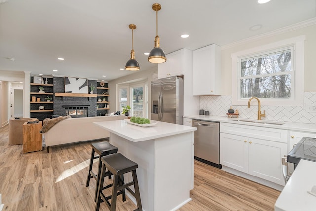 kitchen with stainless steel appliances, white cabinets, sink, and pendant lighting