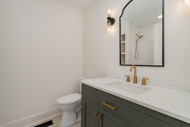 bathroom with toilet, a tile shower, and vanity