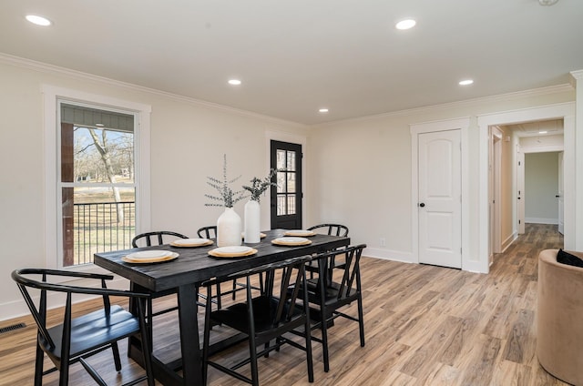 dining area featuring light wood-type flooring and ornamental molding