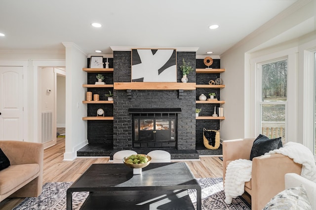 living room with ornamental molding, a brick fireplace, built in shelves, and wood-type flooring